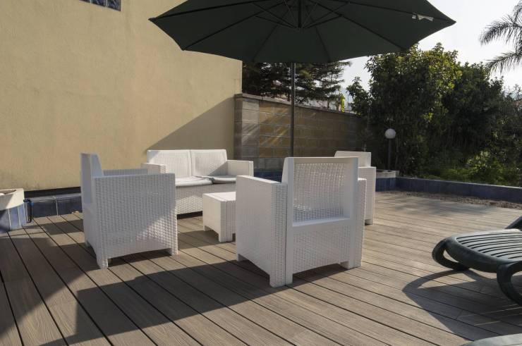 Reserved outdoor relaxation area on teak floor, with chairs, sofa and table