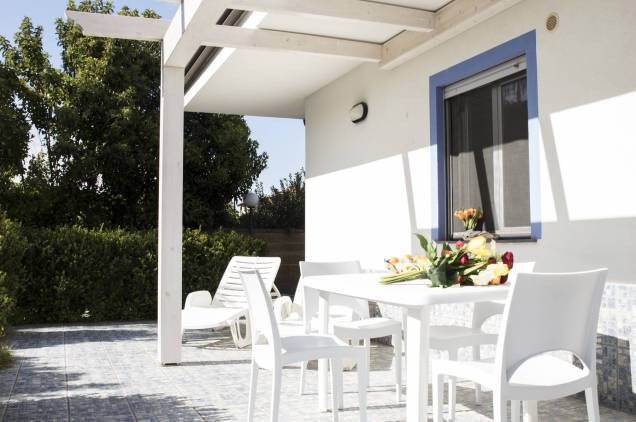 Außenbereich auf der Gartenseite ausgestattet mit kleinem Tisch, Stühlen und Sonnenliegen